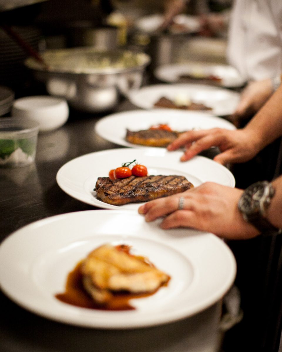 A cook finishing a pan sauce over a low flame