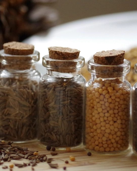 Jars of spice blend and bottles of finishing sauce on a wooden counter
