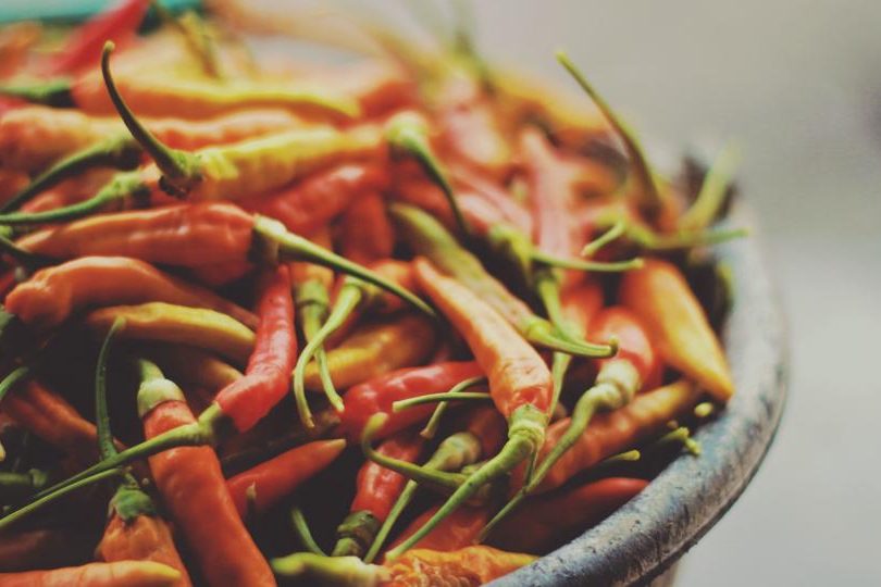 A shallow stone bowl heaped with long dried red and green chillies